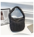 Detailed view of dark grey quilted bucket bag with soft puffy texture on a white pedestal - Gray