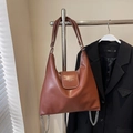 Brown oil wax leather tote bag with flap closure and silver chain details on a hanger - Caramel (No Charm)