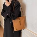Braune Wildleder-Beuteltasche mit Nieten und Schnalle an einem Damenmodell - Braun