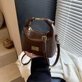 Dark brown faux leather crossbody bag with gold hardware shown in a modern interior setting - Brown