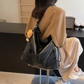 Black large capacity tote bag with bear charm and zippers shown on a shoulder - Black