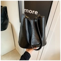 Close-up of the black leather bucket bag texture with gold hardware and HOCOMU logo - Black