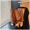 Detail of the brown leather tote bag showing textured surface and HOGOMU branding logo - Brown