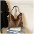 Brown vintage faux leather tote bag with unique side woven labels on a silver suitcase - Brown