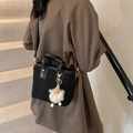 Schwarze Bucket-Bag aus Teddyfell mit Monster-Anhänger und Lederriemen am Modell - Schwarz mit Anhänger