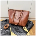 Detalle de la textura de un bolso tote de cuero sintético con correa ajustable - Marrón