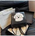 Detailansicht des schwarzen Lederrucksacks mit weißer Plüsch-Hunde-Stickerei in einer Geschenkbox - Schwarz