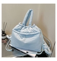 Macro shot of light blue quilted tote bag with padded handles and drawstring closure - Blue