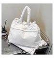 Close-up of a white quilted puffer tote bag with drawstring closure and soft texture - White
