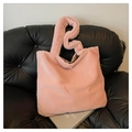 Bolso tote de piel sintética rosa con asas suaves sobre un sofá de cuero negro elegante - Rosa