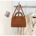 Gros plan d'un sac Boston matelassé marron caramel avec texture litchi et détails métalliques - Marron