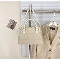 Détail du sac Boston matelassé crème avec texture litchi suspendu à un portant - Blanc