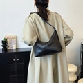 Bolso hobo minimalista de cuero negro con correa ajustable sobre una gabardina beige - Negro