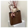 Brown litchi leather bucket handbag with decorative silk scarf on minimalist pedestal - Brown
