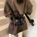 Borsa a bauletto nera lucida con nappe e dettagli argentati portata a tracolla - Nero con ciondolo