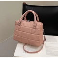 Sac Boston rose en cuir matelassé avec double poignée et bandoulière sur un livre - Rose