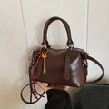 Borsa Boston marrone scuro lucido con ciondolo chiave dorata e tracolla intrecciata - Caffè con Ciondolo