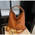 Detail of caramel canvas shoulder bag showing front leather fashion logo and side pockets - Brown