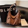 Detailaufnahme der braunen Weichledertasche mit Reißverschlüssen und Schleifendetails - Braun