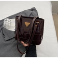 Detalle de bolso tote trenzado marrón con logotipo dorado sobre una americana - Café (Sin Colgante)