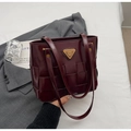 Detalle de bolso tote trenzado burdeos con placa de marca triangular dorada y acabado brillante - Rojo Ankara (Sin Colgante)