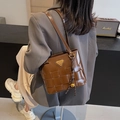 Sac cabas marron tissé avec logo métallique et breloque cloche porté par un mannequin - Marron (Avec Pendentif)