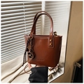 Braune Leder-Eimertasche mit Schokoladenanhänger und Goldnieten am Fensterbrett - Braun