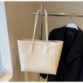 Bolso tote minimalista crema con asas largas junto a una chaqueta de trabajo negra - Blanco Roto