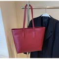 Detail of red leather tote bag with slim shoulder straps on a professional outfit - Burgundy