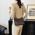 Bolso tipo cubo de cuero marrón oscuro llevado por modelo en un interior elegante - Ciruela Oscura