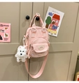 Detailed view of a pink nylon mini bag with plush puppy charm and lucky patch - With Charm / Pink
