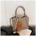 Détail du sac seau en cuir grainé taupe avec charm de chien en peluche et pompon - Avec Pendentif / Gris