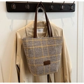 Close-up of yellow and brown houndstooth tweed tote bag with leather handles on a trench coat - Khaki
