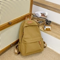 Detailsicht des gelben Nylon-Schulrucksacks mit Leder-Logo und praktischen Seitentaschen - Braun