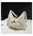 Detail of off-white padded nylon shoulder bag with drawstring pocket on a white table - White