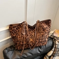 Large leopard print tote bag with brown slim handles on a black leather surface - Brown
