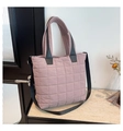 Close-up of quilted nylon fabric and black reinforced handles on a pink tote bag - Purple