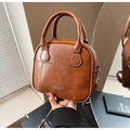 Detalle de bolso vintage en cuero marrón con diseño de retazos y asas redondas elegantes - Marrón