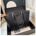 Detalle de bolso tote de cuero negro con grano litchi y logotipo dorado elegante - Negro