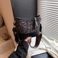 Chic leopard print bucket bag with wide strap and tassel detail in a stylish setting - Black