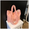 Primer plano del bolso tote de felpa rosa con textura suave y etiqueta de marca - Rosa