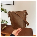 Detail shot of a brown vintage leather bucket bag with metallic buckle in retro setting - Brown