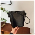 Detailed close-up of glossy black leather bucket bag with silver buckle and vertical stitching - Black