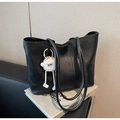 Detalle de un bolso tote negro grande con asas largas y un colgante de monstruo de peluche - Negro con colgante