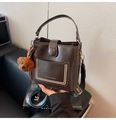 Detailansicht der dunkelbraunen Eimertasche mit bedrucktem Schultergurt und Bären-Anhänger - Mit Anhänger / Braun