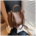 Detailansicht der braunen Leder-Eimertasche mit gewebtem Quasten-Anhänger und Schultergurt - Braun Mit Dekorativem Anhänger