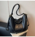 Detail of black faux leather tote with circular quilted logo and gold hardware accents - Black