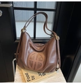 Detail of embossed round logo on brown vintage soft leather hobo bag with dual shoulder straps - Brown
