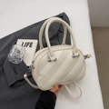 Dettaglio della borsa color crema con trama a litchi su un blazer grigio chic - Bianco avorio