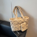 Beige quilted tote bag with floral embroidery and mini pouch set on a black sofa - Khaki